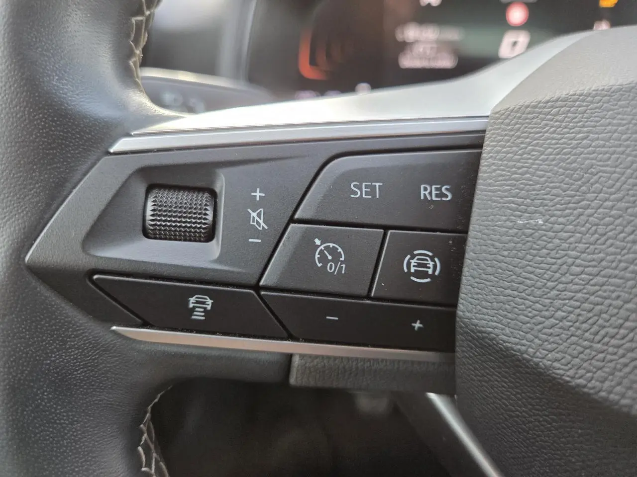 Gros plan sur les commandes multifonctions du volant de la SEAT IBIZA 2025, boutons noirs avec symboles blancs.