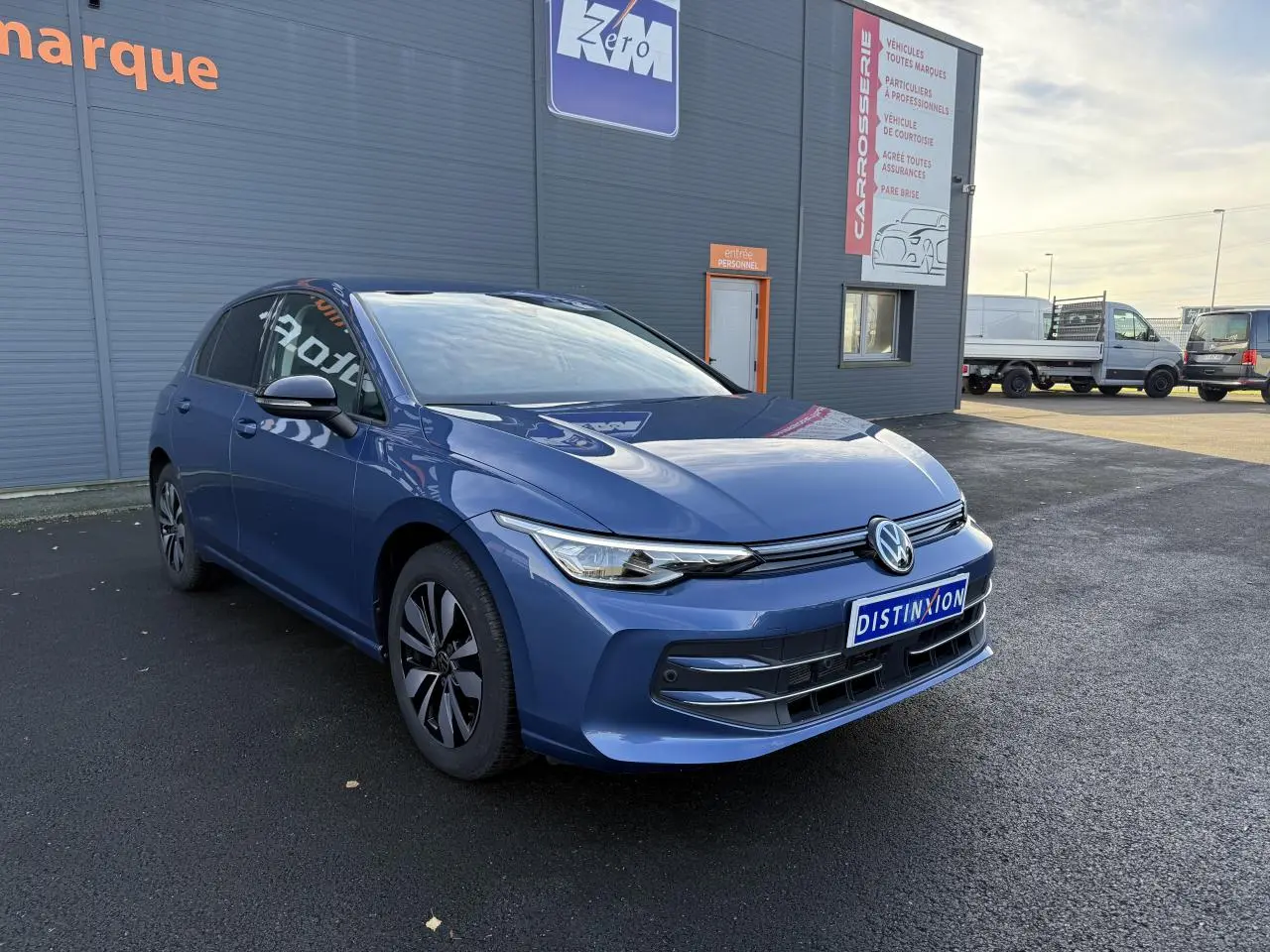 Volkswagen Golf 2025 bleu anémone métallisée vue 3/4 avant avec projecteurs LED et jantes distinctives.