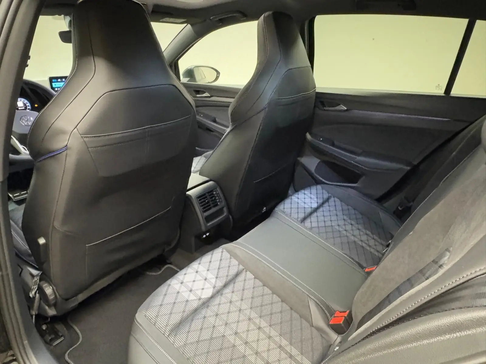 Vue intérieure arrière côté droit de la Volkswagen Golf 2.0 TDI R-Line 2026, sièges en cuir noir et tissu gris à motifs.