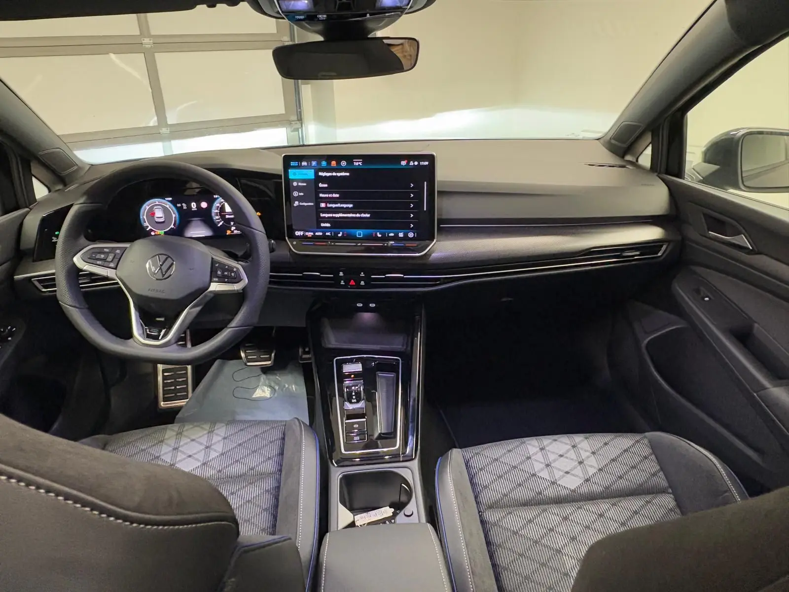 Vue intérieure avant de la Volkswagen Golf 2.0 TDI R-Line 2026, avec tableau de bord moderne et sièges tissu noir à motifs.