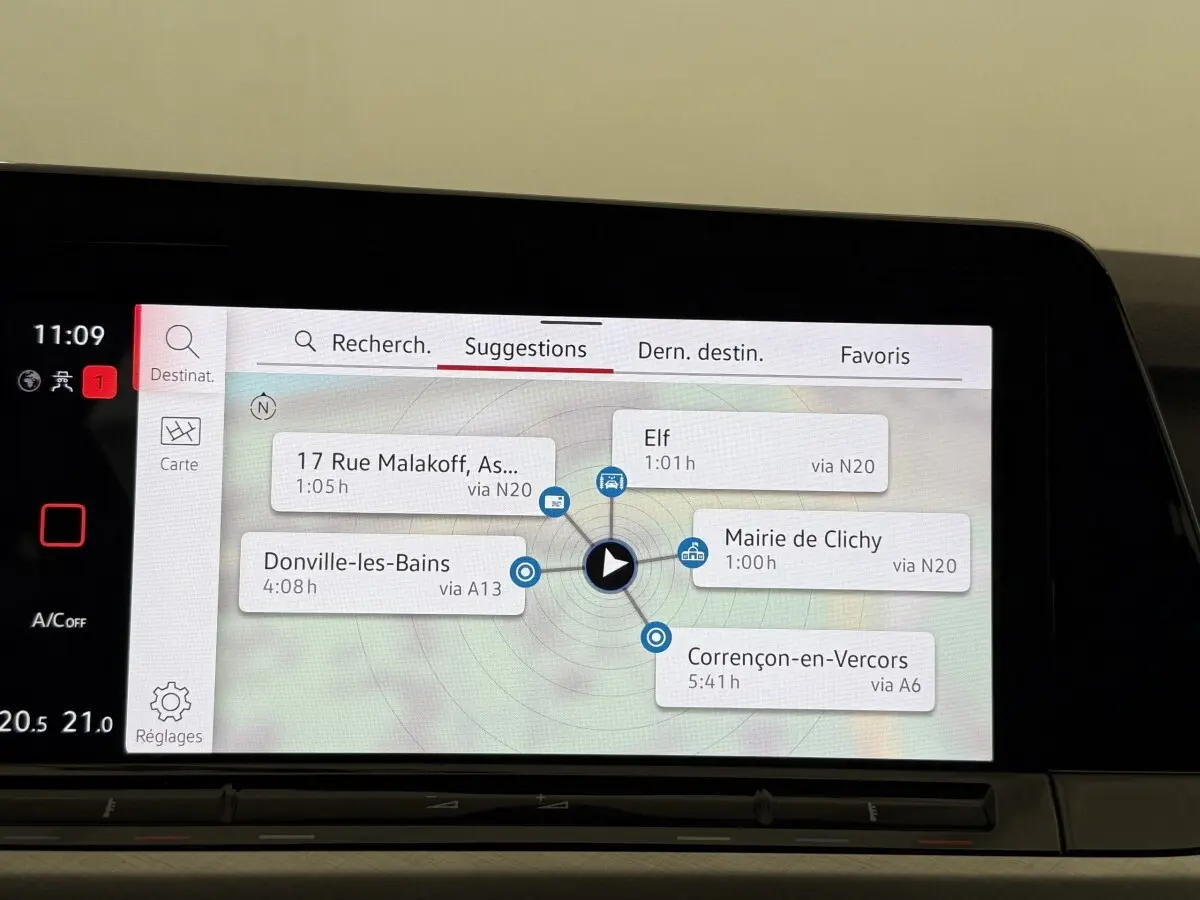 Écran tactile central du tableau de bord de la Volkswagen Golf bleu, affichant le menu de navigation avec suggestions d’itinéraires.