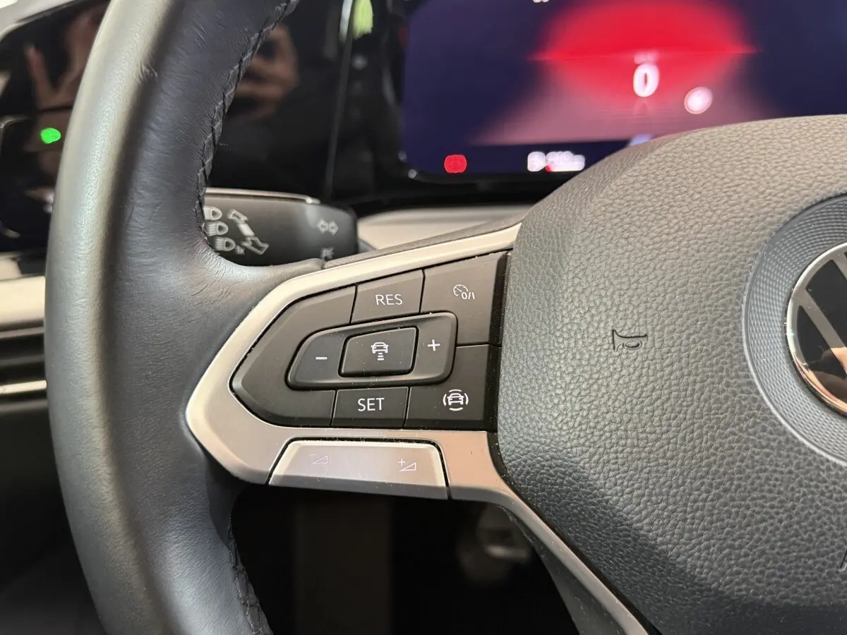 Gros plan sur le volant cuir de la Volkswagen Golf bleu 2021, avec commandes du régulateur adaptatif visibles.