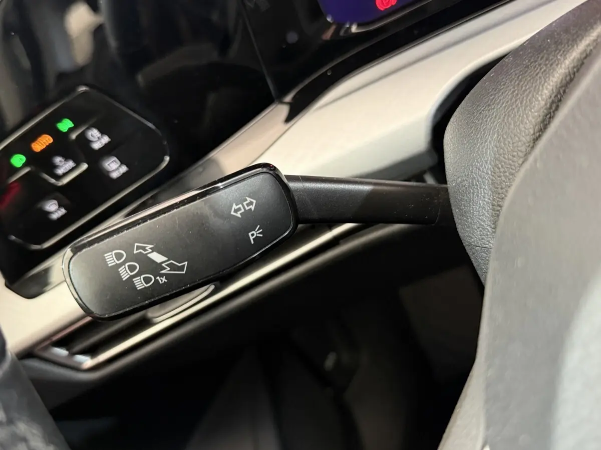 Gros plan sur la commande de clignotants noire dans l’habitacle de la Volkswagen Golf bleu, avec tableau de bord en arrière-plan.