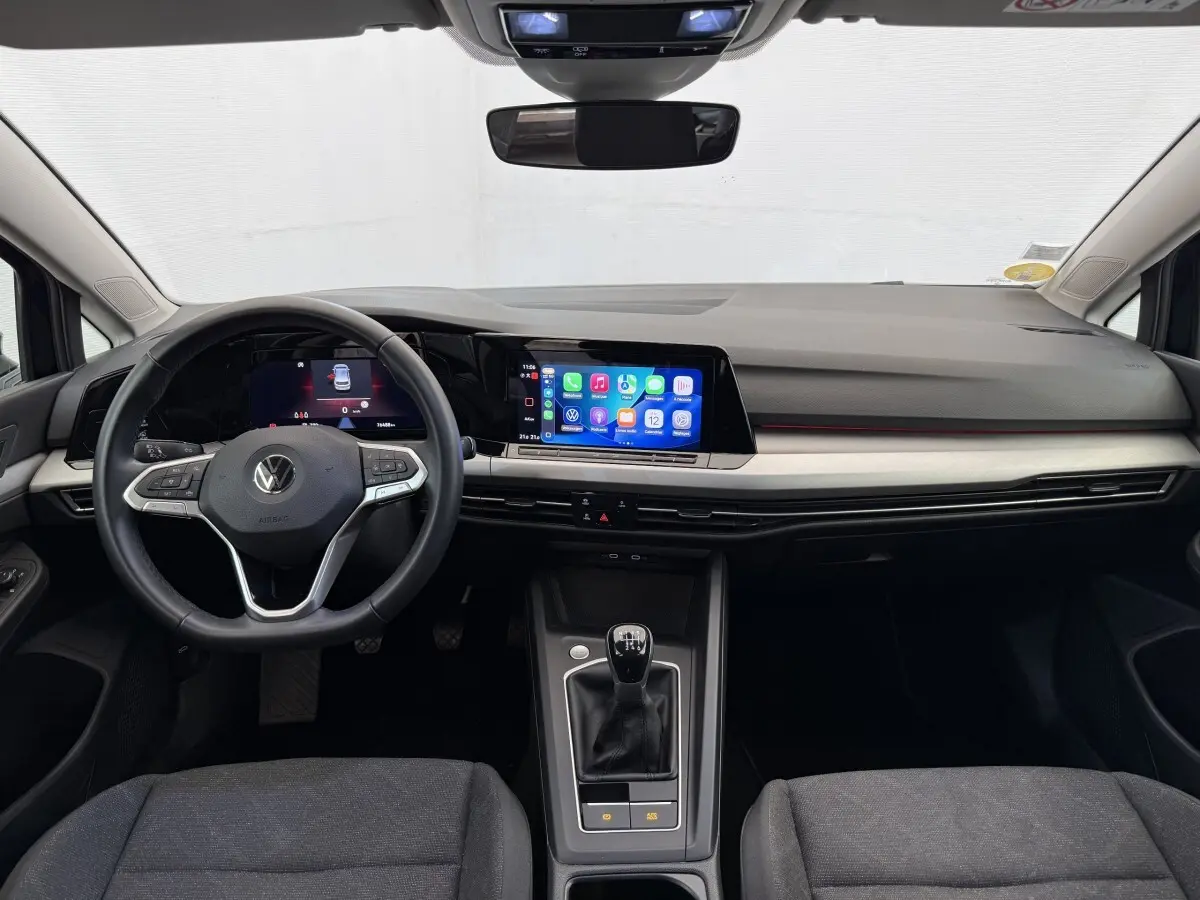 Vue frontale de l'intérieur de la Volkswagen Golf 2.0 TDI Life 2021 avec tableau de bord noir, écran tactile et volant cuir.