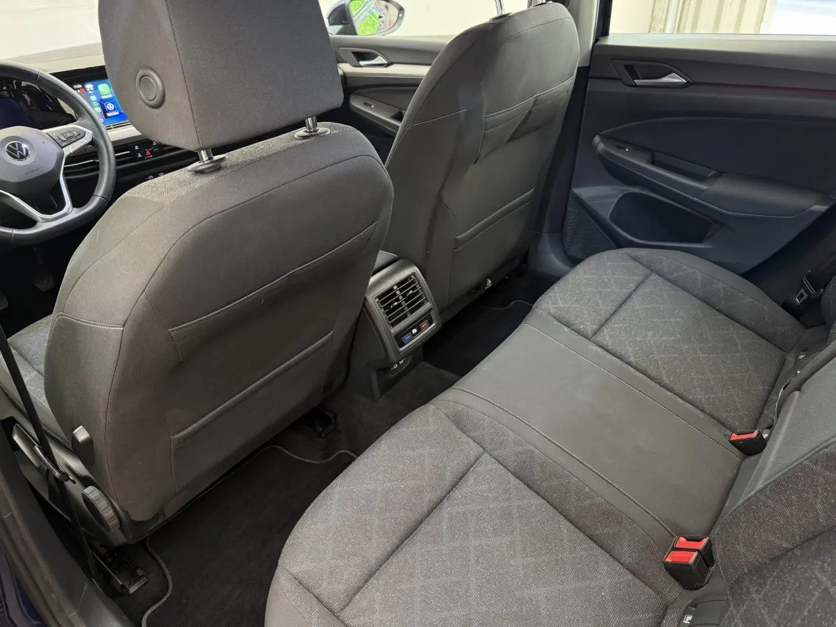 Vue intérieure arrière côté droit de la Volkswagen Golf bleu 2021, montrant les sièges et la console centrale avec aérateurs.