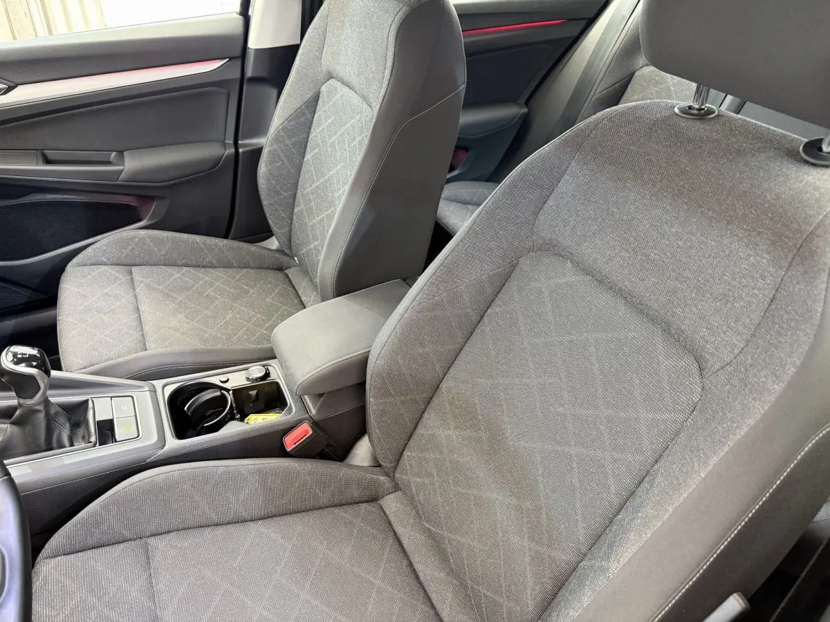Vue intérieure rapprochée des sièges avant gris et de la console centrale avec levier de vitesse manuelle d’une Volkswagen Golf 2021.