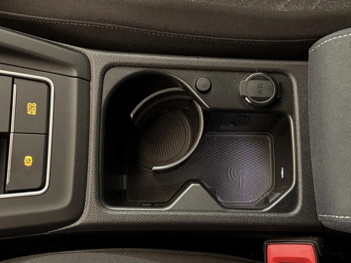 Vue rapprochée de la console centrale noire d’une Volkswagen Golf 2.0 TDI 2021 avec prise 12V et zone de recharge sans fil.