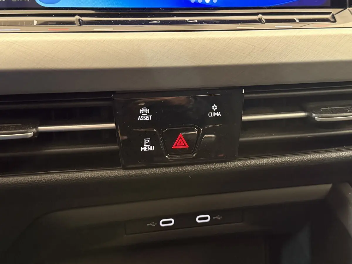 Gros plan sur la console centrale noire de la Volkswagen Golf bleu 2021, avec boutons d'alerte et climatisation.