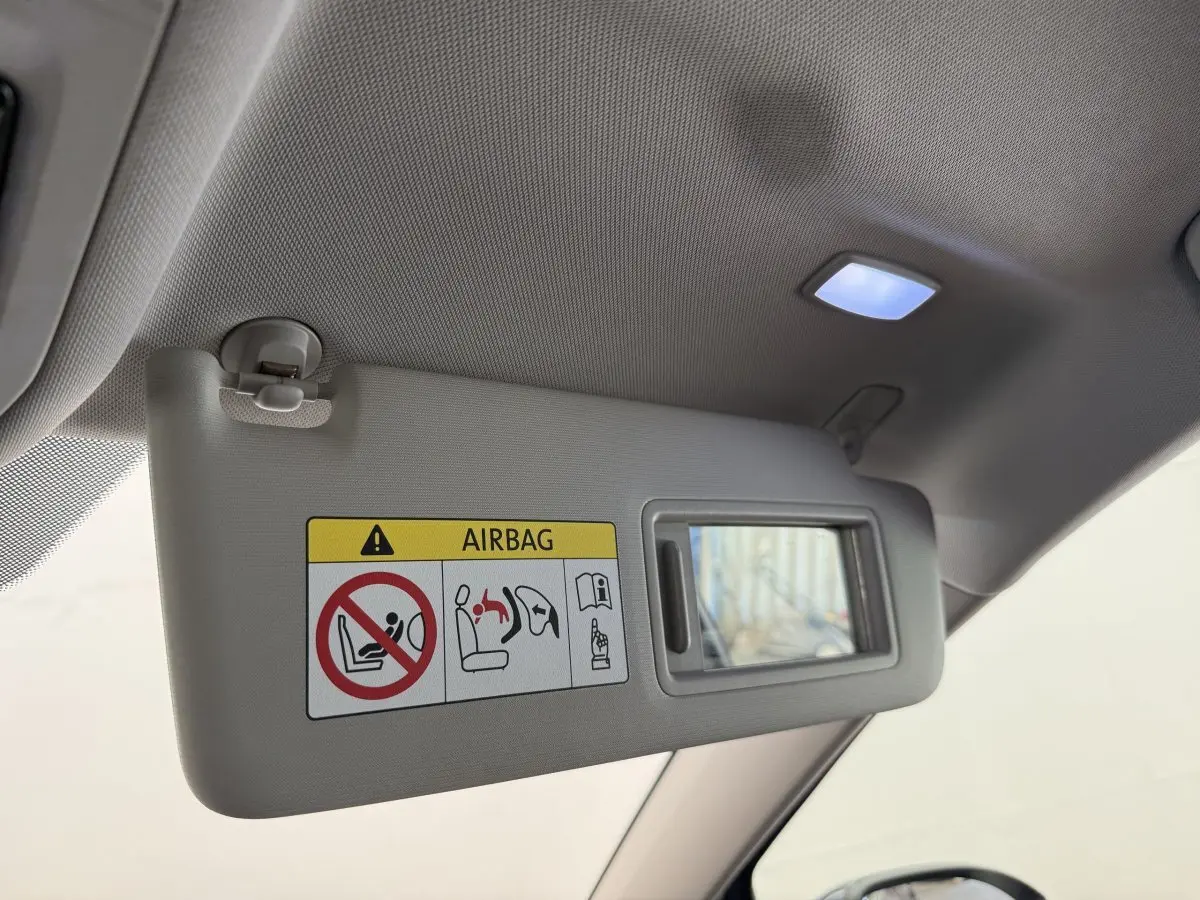 Détail du pare-soleil côté conducteur avec miroir intégré et avertissement airbag dans un Volkswagen Golf bleu 2021.
