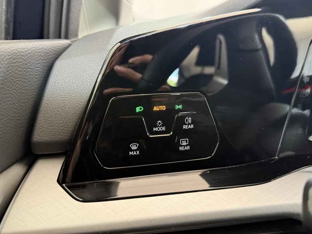 Gros plan sur le panneau de commande d’éclairage noir brillant du tableau de bord intérieur d’une Volkswagen Golf bleue.