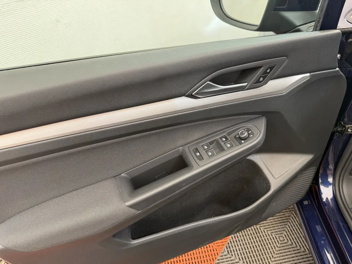 Vue rapprochée de la porte avant gauche bleu foncé de la Volkswagen Golf 2.0 TDI avec commandes électriques et poignée argentée.