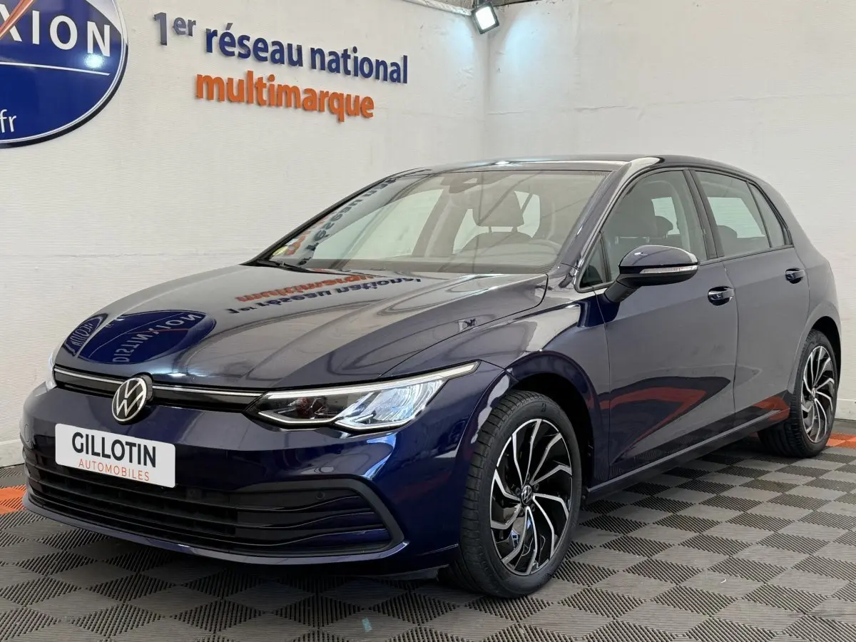 Volkswagen Golf 2.0 TDI bleu en 3/4 avant droit, avec jantes alliage et phares LED allumés.