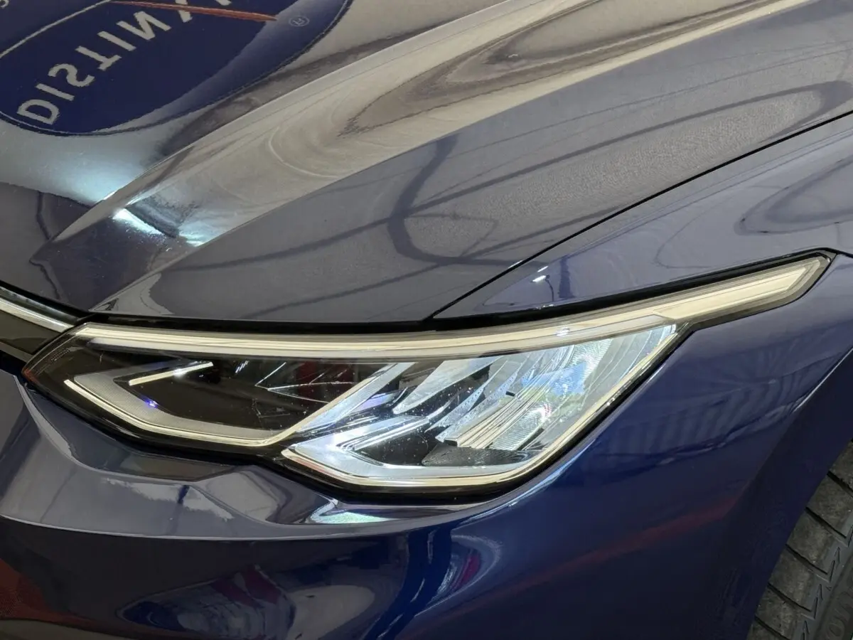 Gros plan sur le phare avant droit bleu métallisé d'une Volkswagen Golf 2.0 TDI 2021 avec ligne LED distinctive.