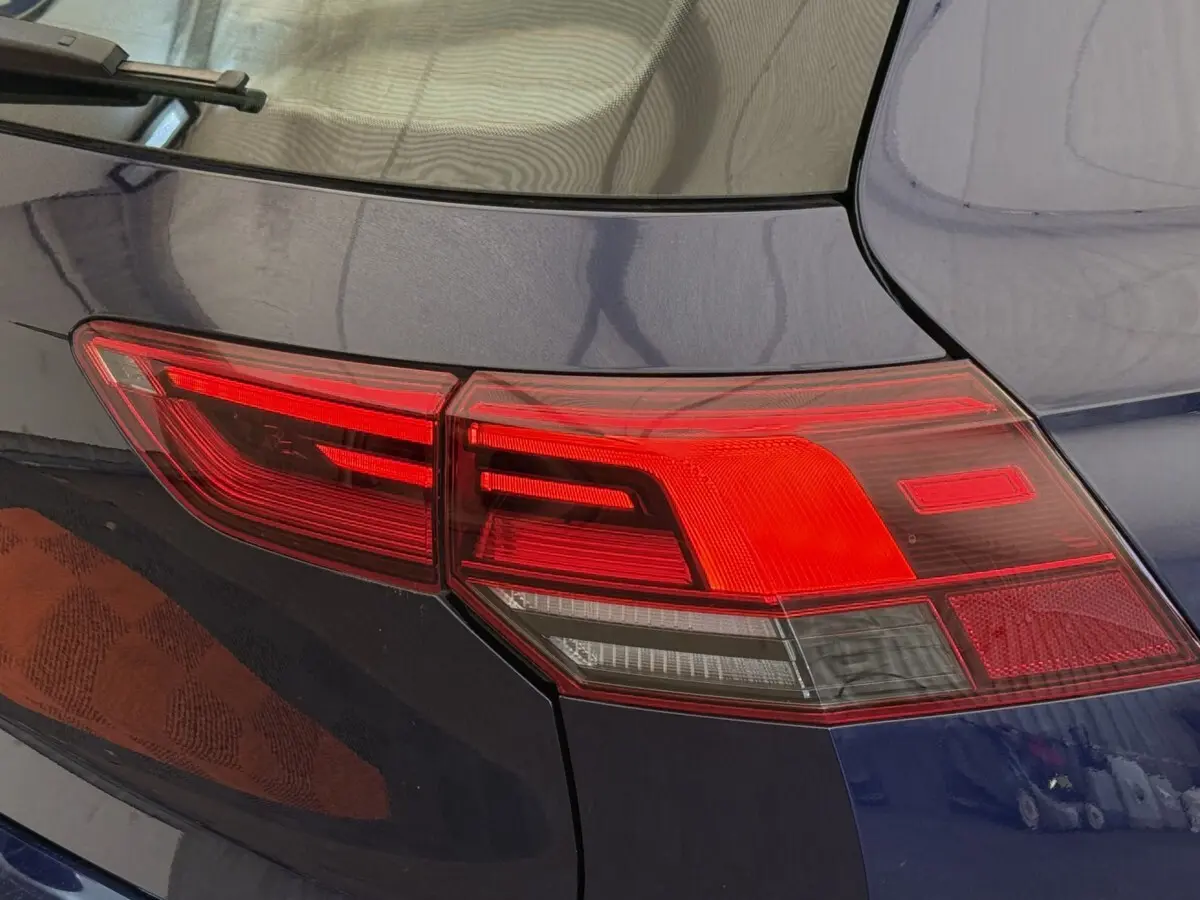 Feu arrière droit rouge et blanc sur Volkswagen Golf bleu, vue rapprochée du coin arrière du véhicule.