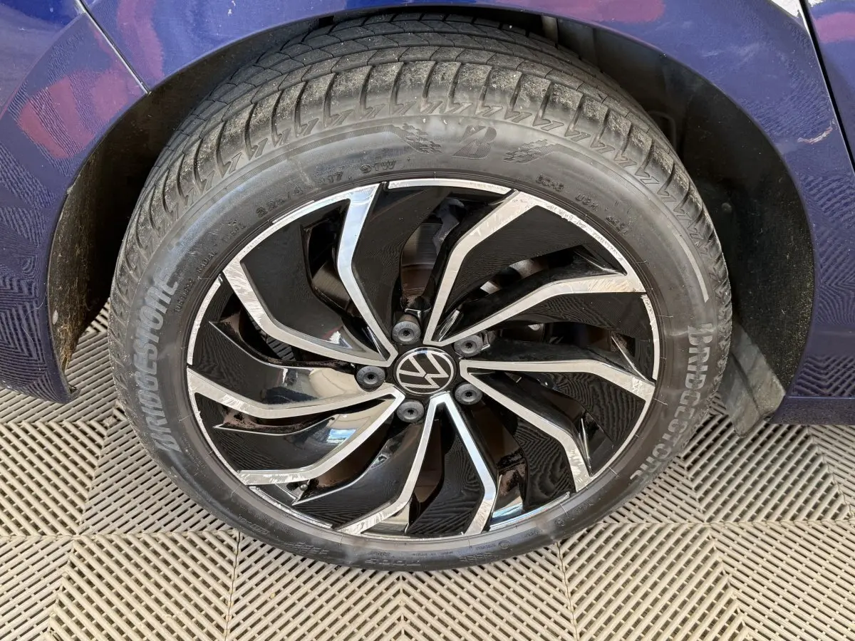 Gros plan sur la roue avant droite d’une Volkswagen Golf bleu 2021 avec jante noire et argentée au design dynamique.
