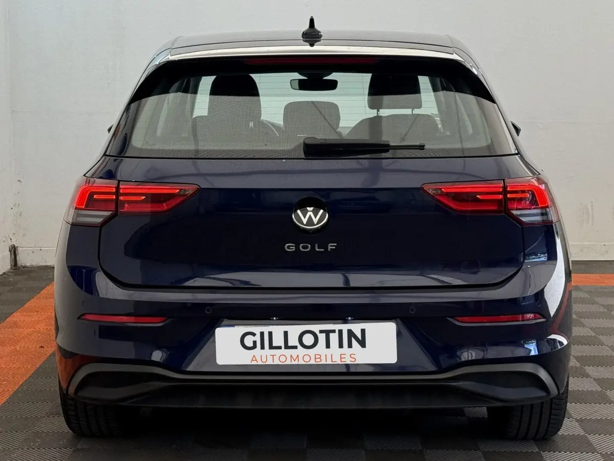 Vue arrière d'une Volkswagen Golf bleu foncé avec feux LED et logo centré sur fond blanc.