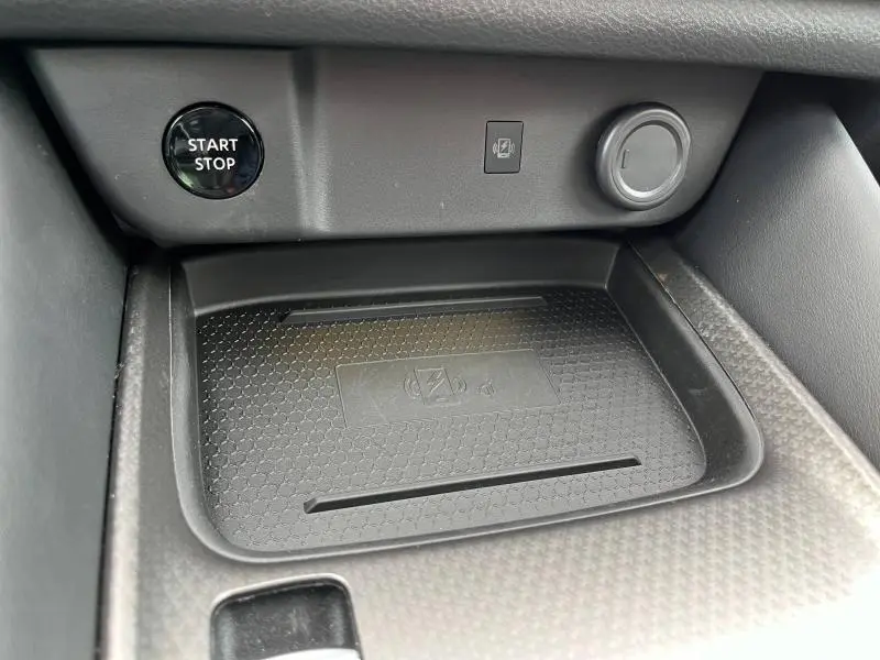 Détail de la console centrale noire du Nissan Qashqai e-POWER 2024 avec bouton Start/Stop et chargeur sans fil intégré.