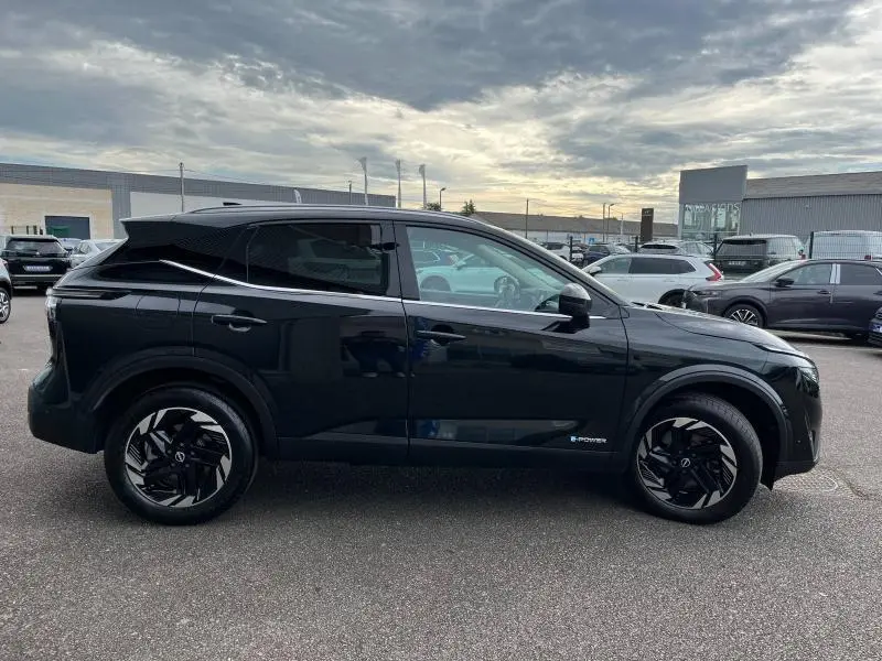 Profil côté gauche du Nissan Qashqai e-POWER 2024 noir Kuro métallisé avec jantes alliage noires et vitres teintées.