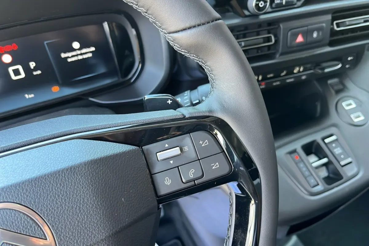 Vue rapprochée du volant cuir noir du Citroën Berlingo 2025 gris artense, avec commandes audio intégrées.