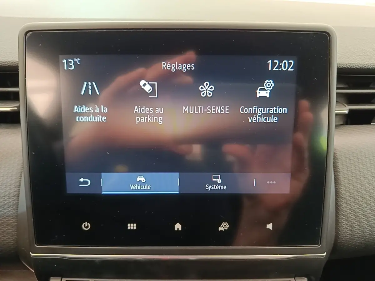 Écran tactile central de la Renault Clio Intens gris foncé, affichant les réglages d’aides à la conduite et parking.