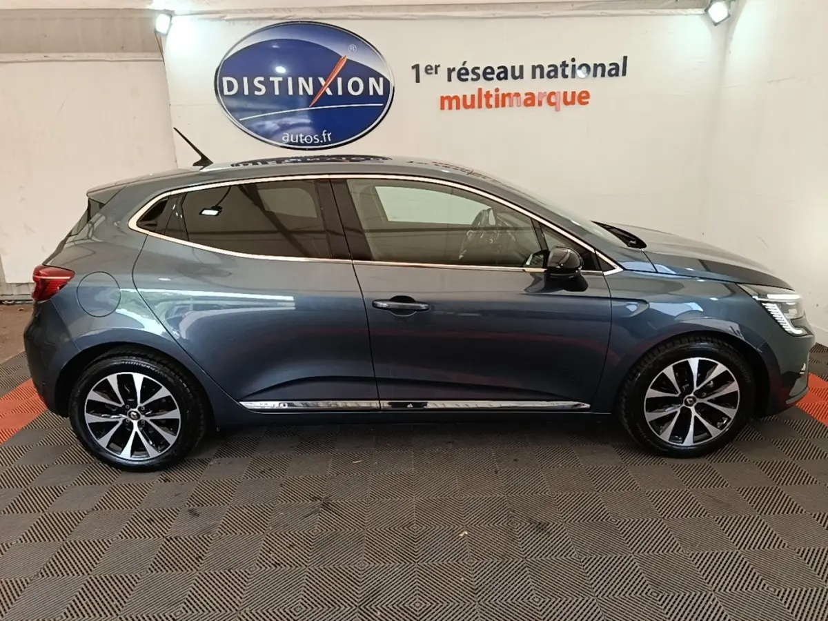 Profil droit d'une Renault Clio Intens TCe 100 gris foncé avec jantes alliage et vitres teintées en intérieur showroom.
