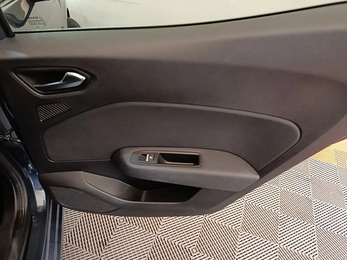 Vue intérieure de la porte côté gauche d'une Renault Clio Intens TCe 100 2020 gris foncé, avec poignée et commande de vitre.