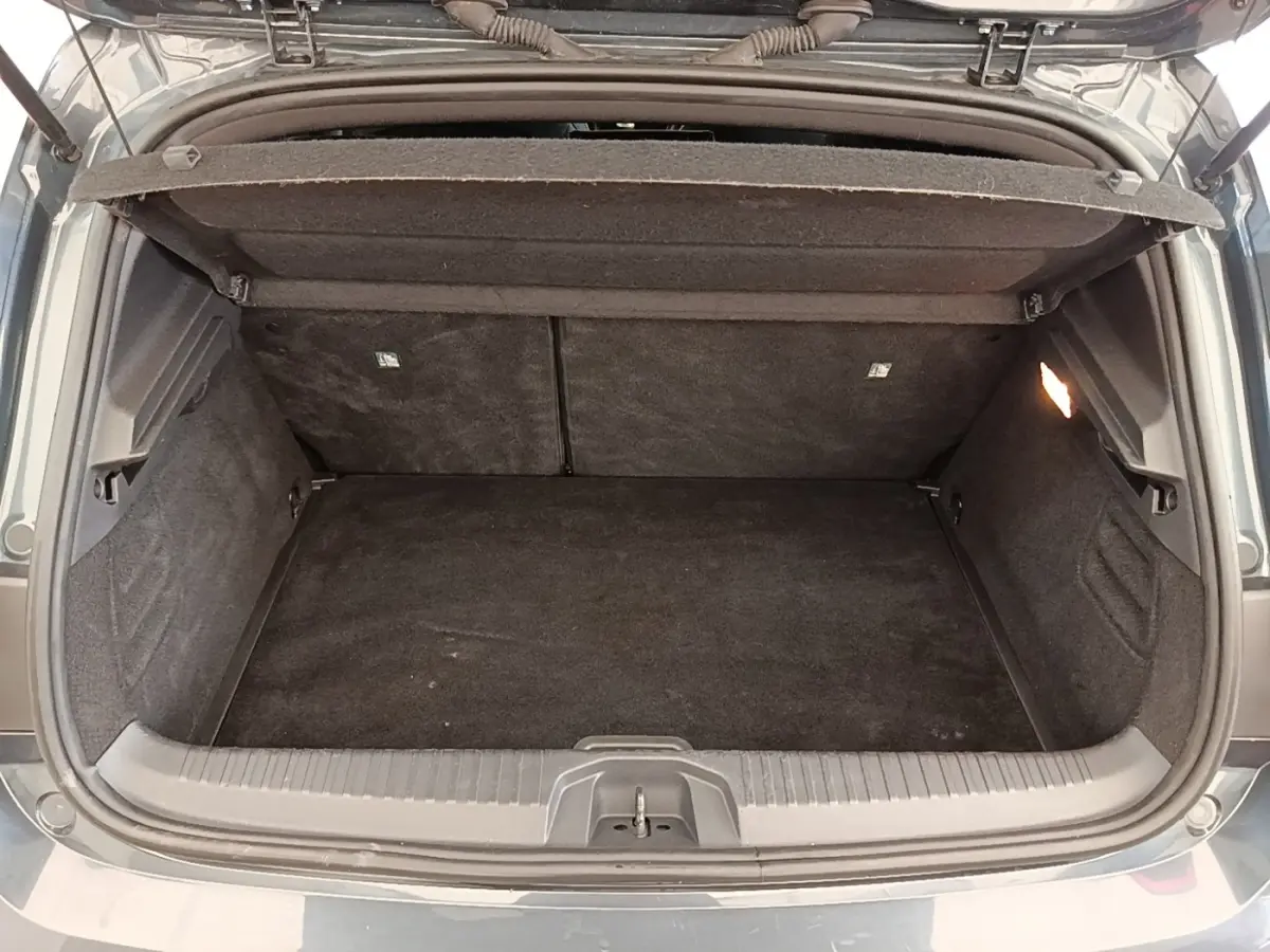 Coffre ouvert vu de l'arrière d'une Renault Clio Intens TCe 100 gris foncé, montrant l'espace de chargement vide.