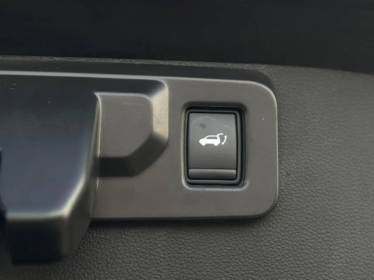 Bouton noir d'ouverture du hayon mains libres sur panneau intérieur du Renault Symbioz E-Tech Full Hybrid 2025.