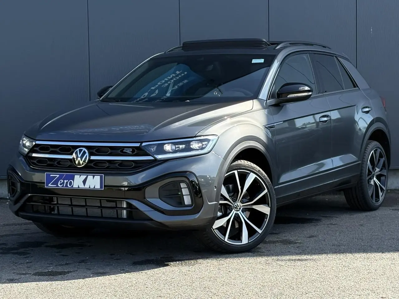 Volkswagen T-Roc gris Indium en 3/4 avant droit avec jantes alliage 19" et toit ouvrant noir.