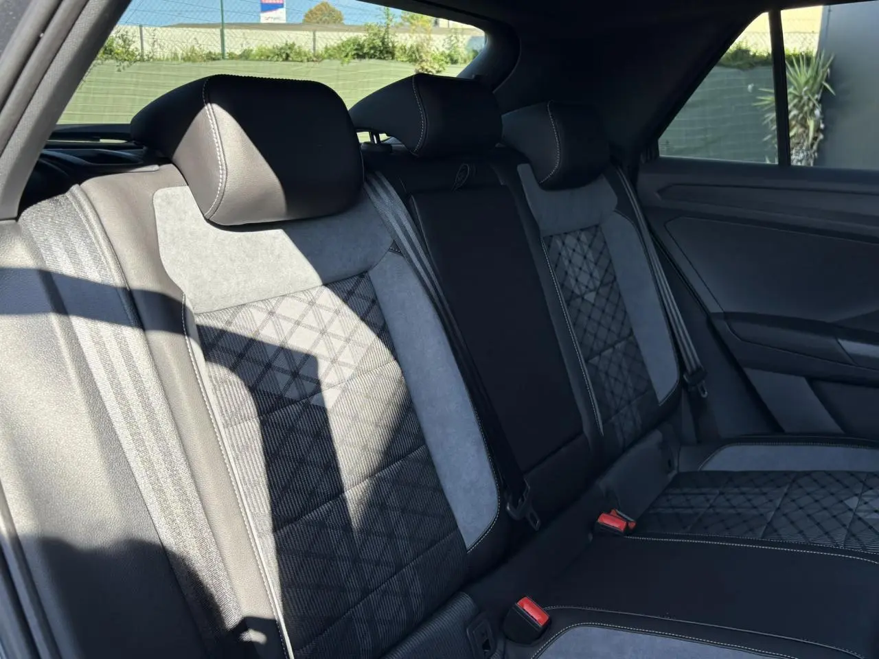 Vue intérieure des sièges arrière en tissu et cuir noir avec surpiqûres blanches du Volkswagen T-Roc gris Indium 2025 R-Line
