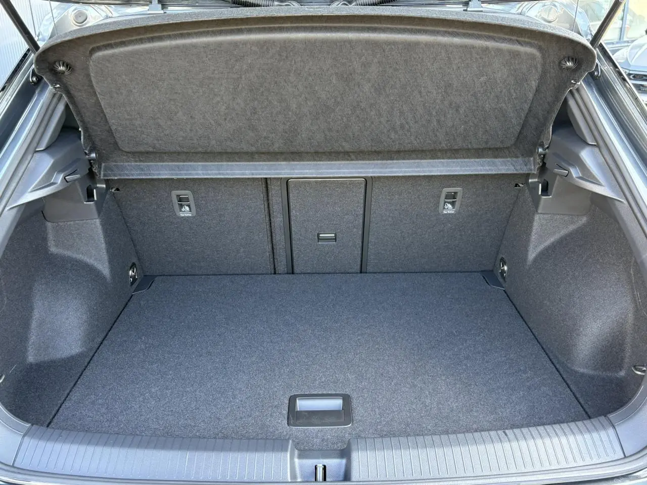 Coffre ouvert du Volkswagen T-Roc gris Indium, montrant l'espace de chargement et la garniture intérieure grise.