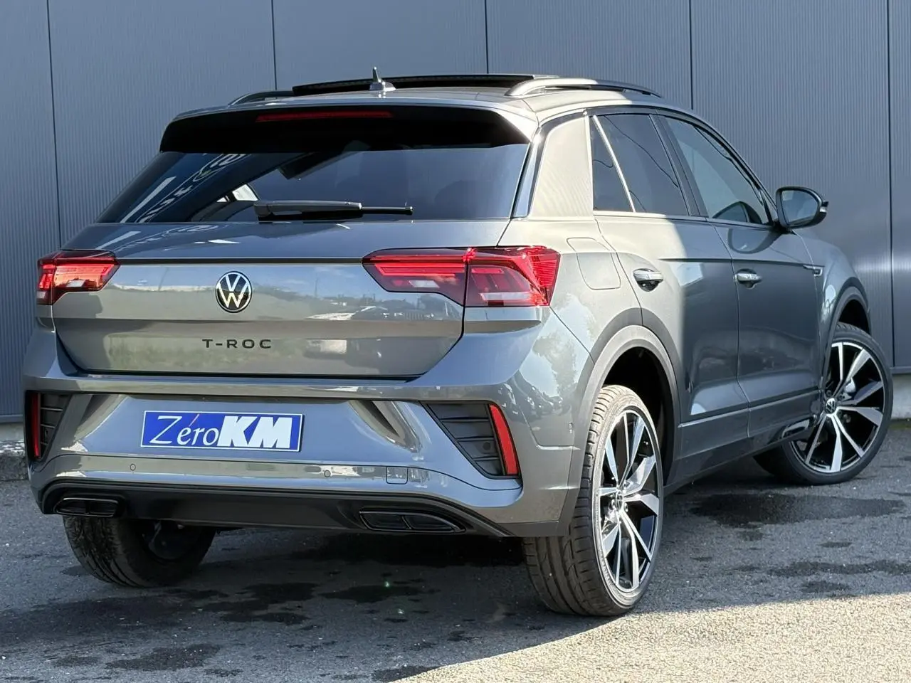 Vue 3/4 arrière droite d'un Volkswagen T-Roc gris Indium avec jantes alliage 19 pouces et vitres teintées.