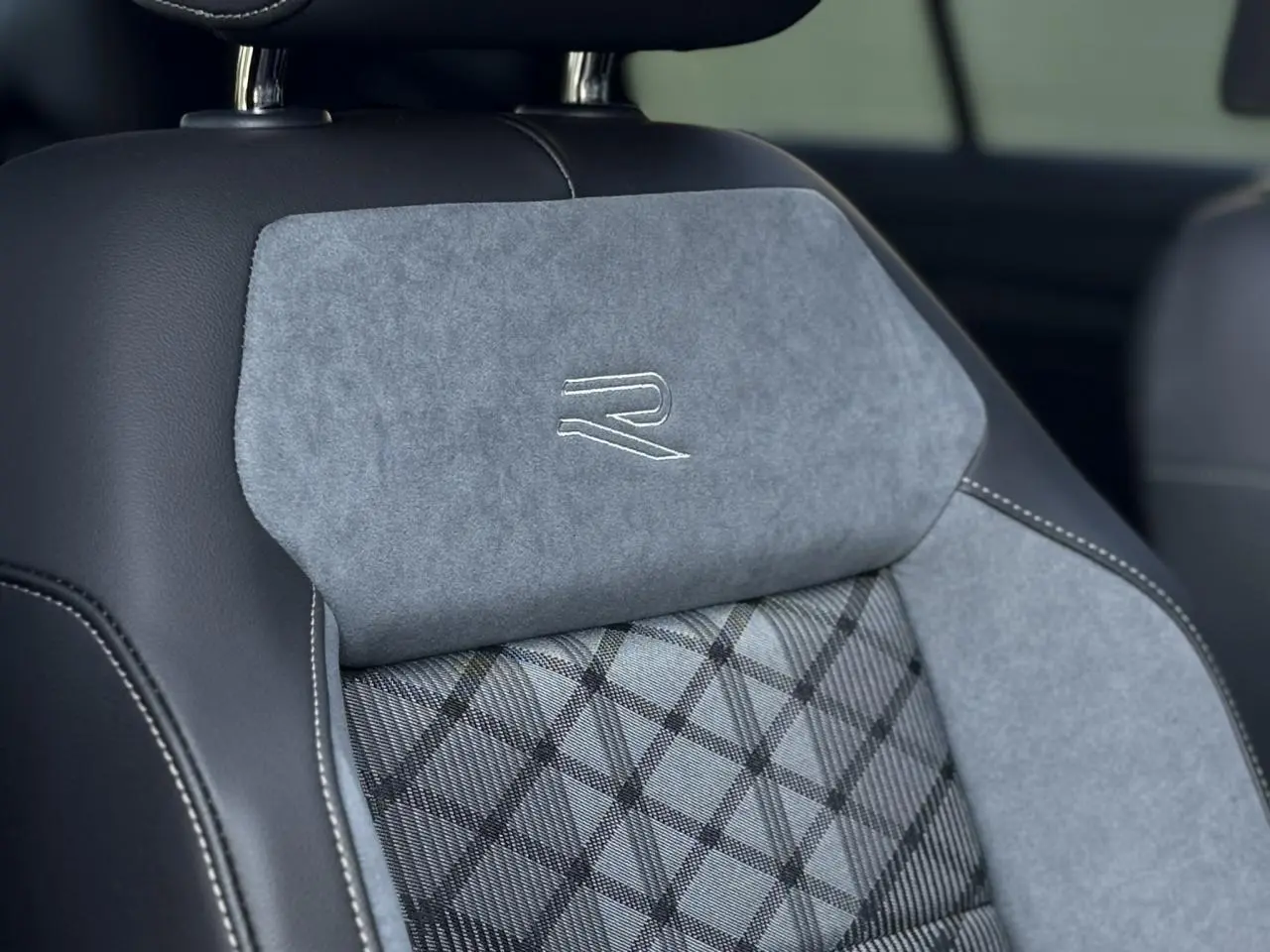 Gros plan sur le siège avant gris et noir du Volkswagen T-Roc 2.0 TDI R-Line avec logo R brodé sur l'appuie-tête