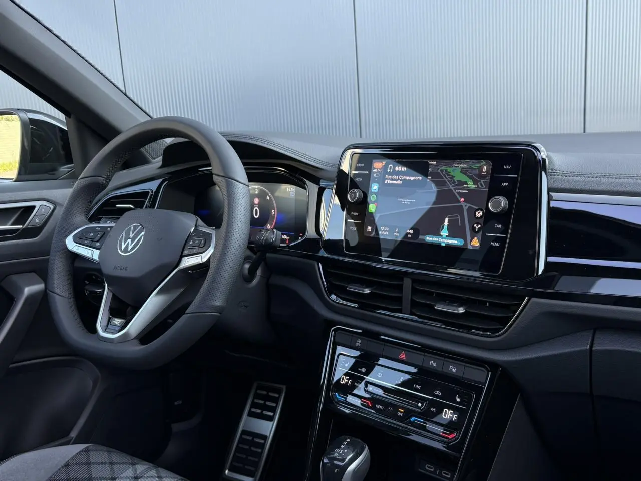 Intérieur du Volkswagen T-Roc 2025 R-Line, vue côté conducteur sur volant cuir, tableau de bord digital et écran tactile central.
