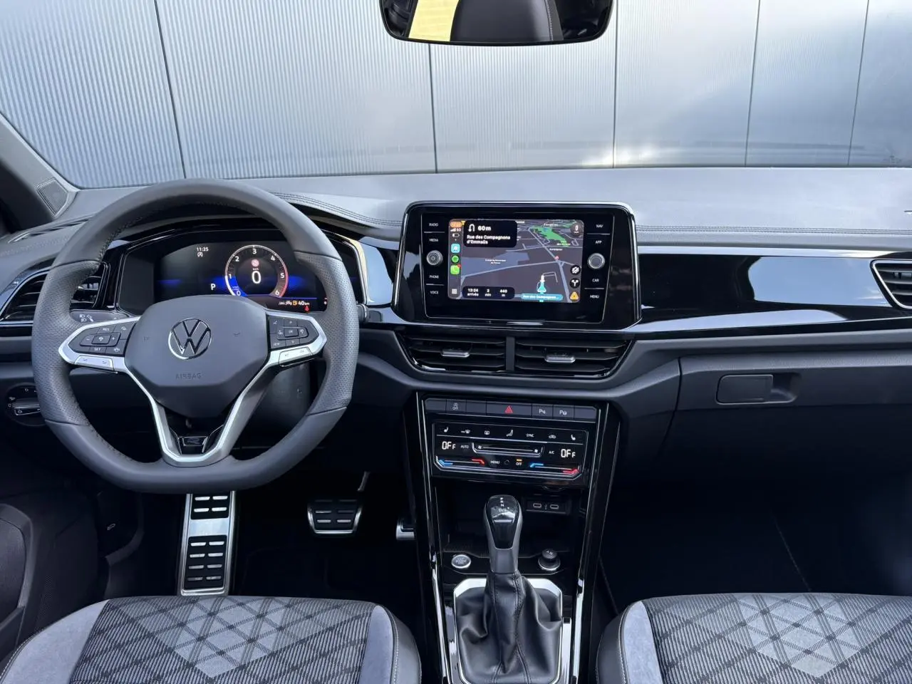 Vue frontale de l'habitacle du Volkswagen T-Roc 2025, tableau de bord noir avec écran tactile et volant multifonction.