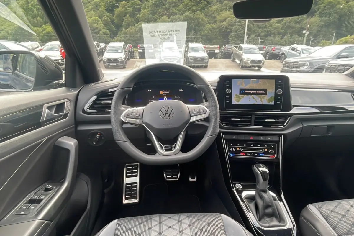 Vue intérieure centrée sur le volant et la console du Volkswagen T-Roc noir grenadilla 2025, finition R-Line Black.