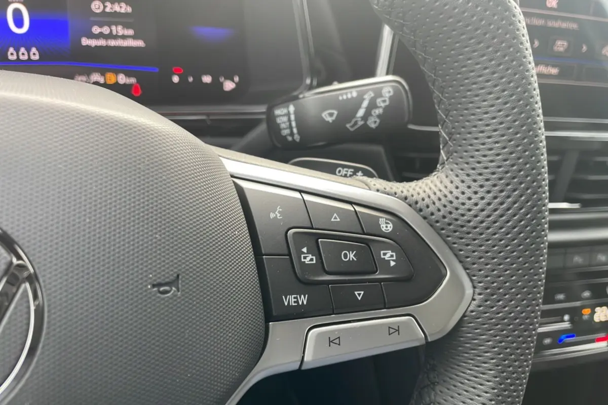 Gros plan sur le volant perforé du Volkswagen T-Roc 2025 R-Line Black avec commandes multifonctions visibles.