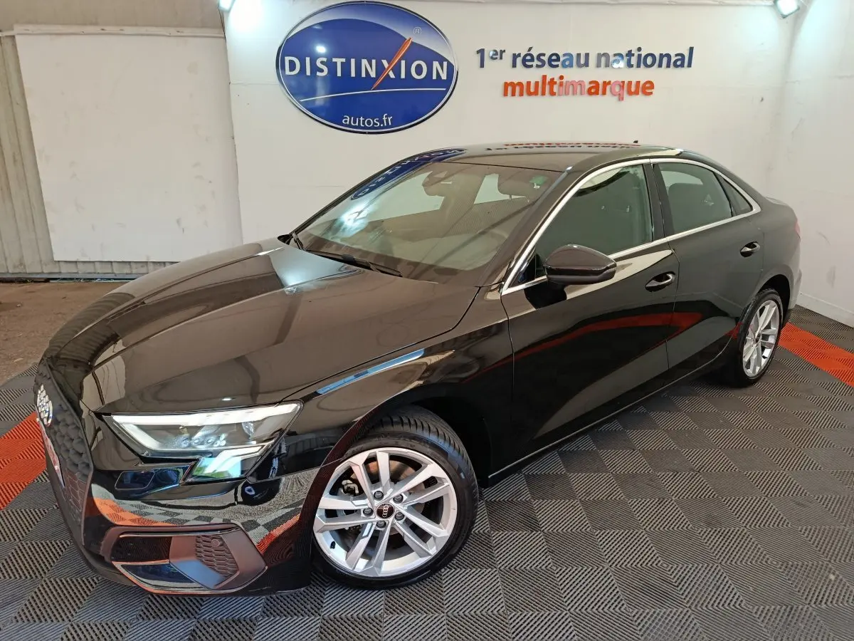 Audi A3 30 TFSI MHEV Business Line noire vue en 3/4 avant droit dans un showroom avec logo Distinxion en arrière-plan