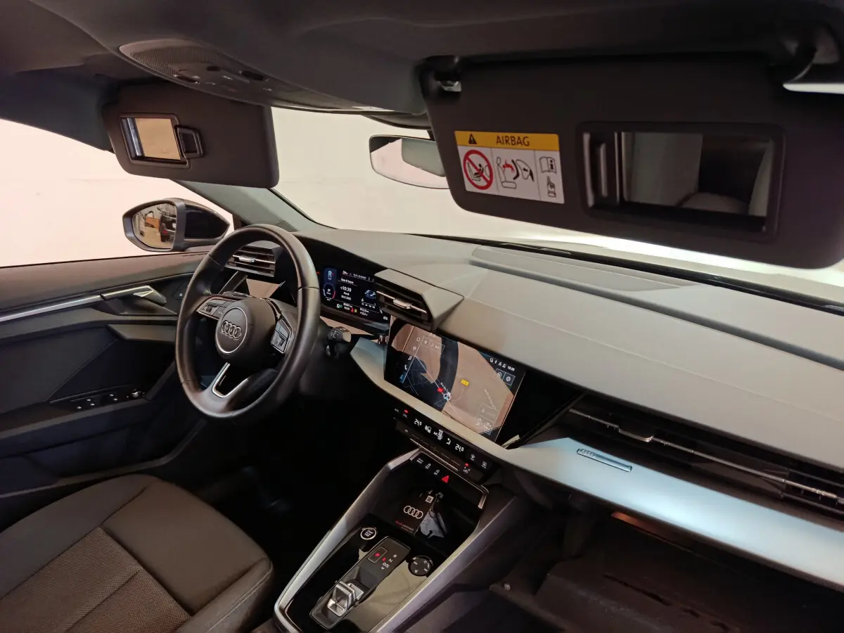 Vue intérieure côté conducteur de l'Audi A3 30 TFSI MHEV 2022, tableau de bord moderne avec écran tactile et volant cuir.