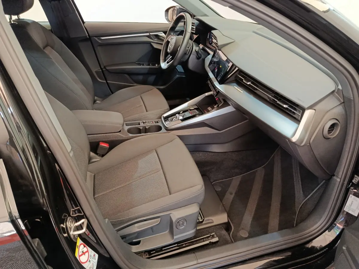 Intérieur avant droit d'une Audi A3 noire 2022, sièges tissu gris, tableau de bord moderne avec écran tactile.