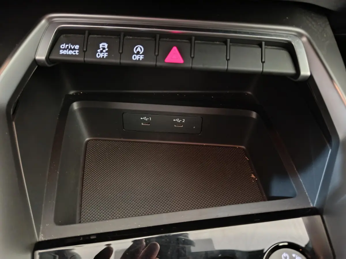 Vue rapprochée de la console centrale noire de l'Audi A3 30 TFSI MHEV avec boutons de contrôle et ports USB visibles.