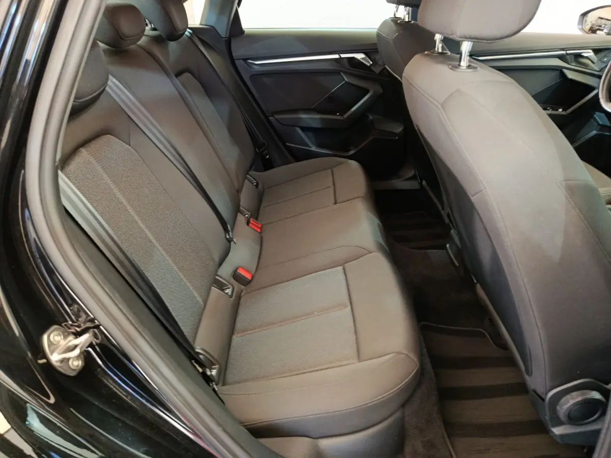 Vue intérieure côté gauche sur la banquette arrière grise de l'Audi A3 30 TFSI MHEV Business Line 2022 noire.