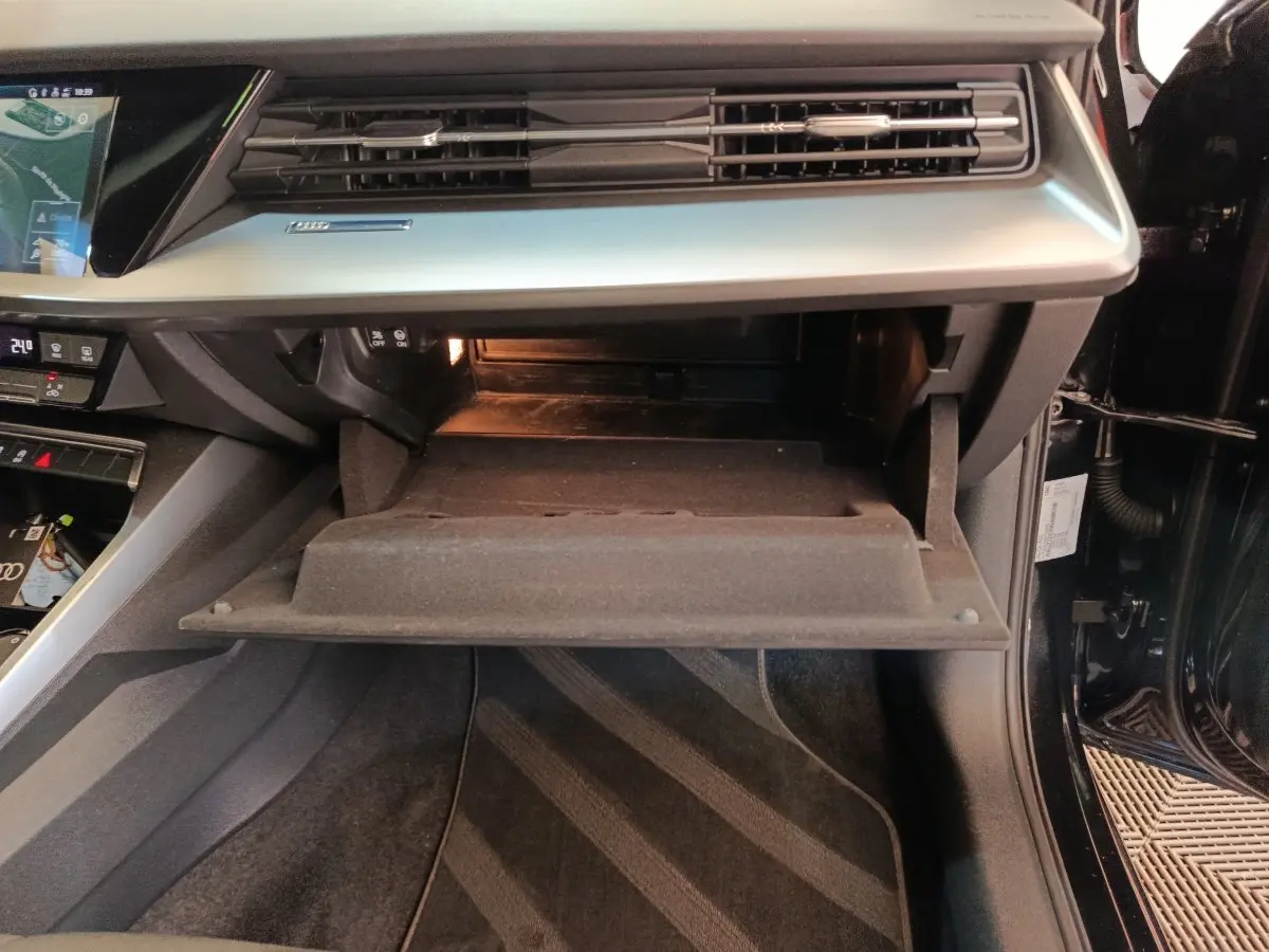 Intérieur de l'Audi A3 2022 noir, vue sur la boîte à gants ouverte côté passager avec tableau de bord gris.