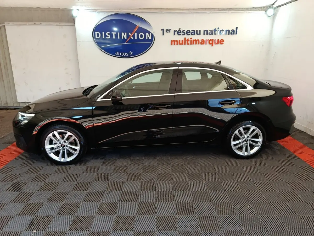 Audi A3 30 TFSI MHEV noir vue de profil côté gauche dans un showroom avec sol à damier noir et rouge.