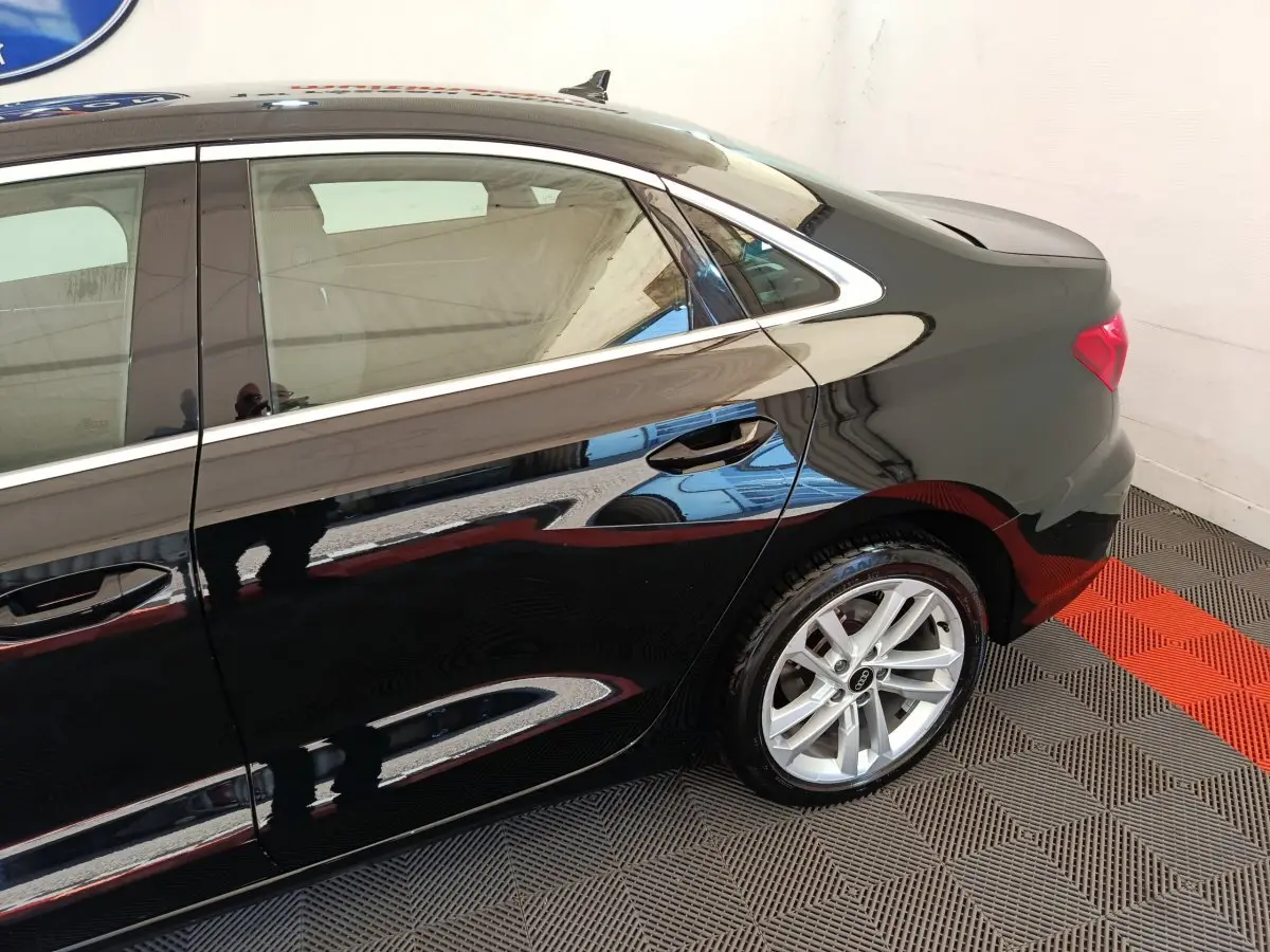Profil arrière droit d'une Audi A3 noire brillante, mettant en valeur la jante alliage et la ligne de toit élégante.