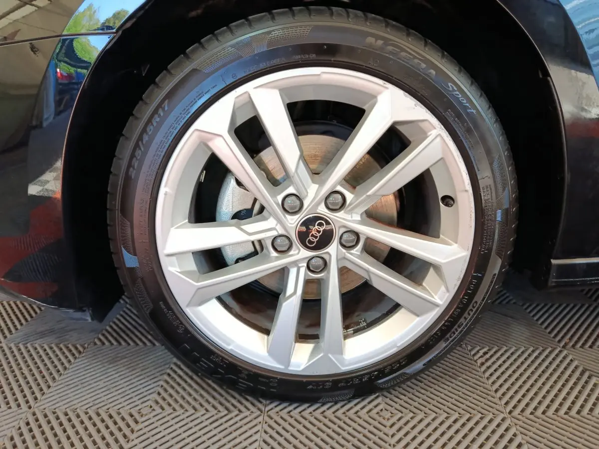 Gros plan sur la jante argentée de l'Audi A3 noire, mettant en valeur le logo Audi au centre de la roue.