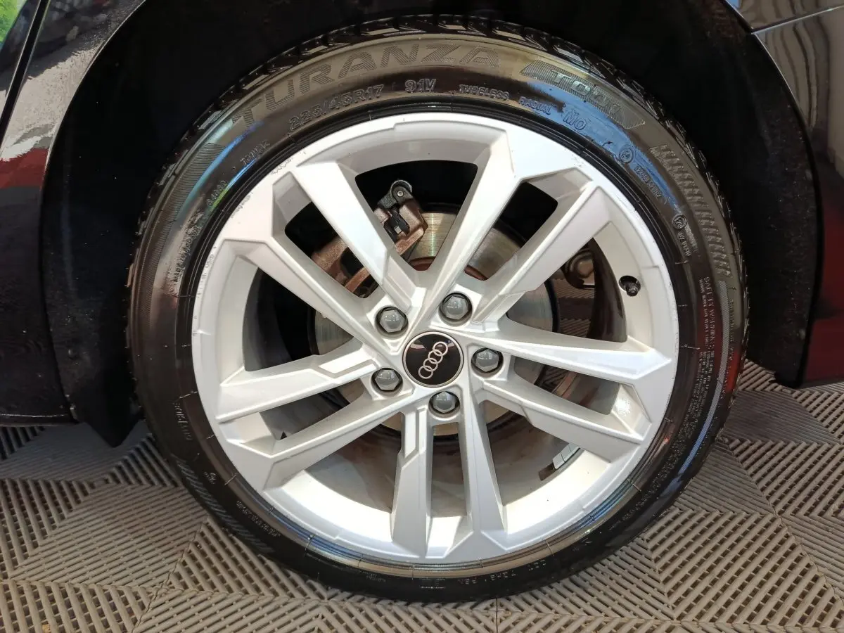 Gros plan sur la roue avant droite noire d'une Audi A3 30 TFSI MHEV avec jante argentée à 5 doubles branches.