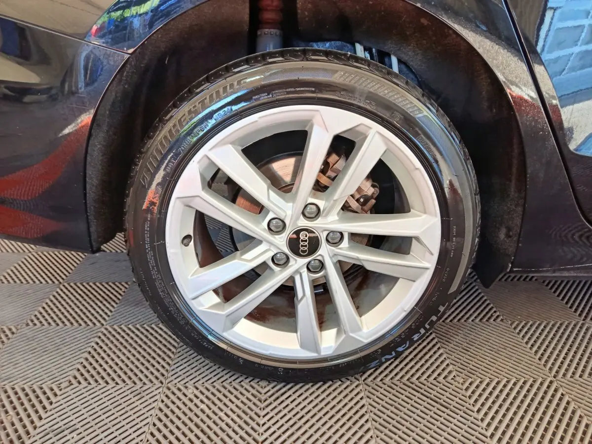 Gros plan sur la roue avant droite d'une Audi A3 noire 2022, mettant en valeur la jante en alliage argentée et le pneu Bridgestone.