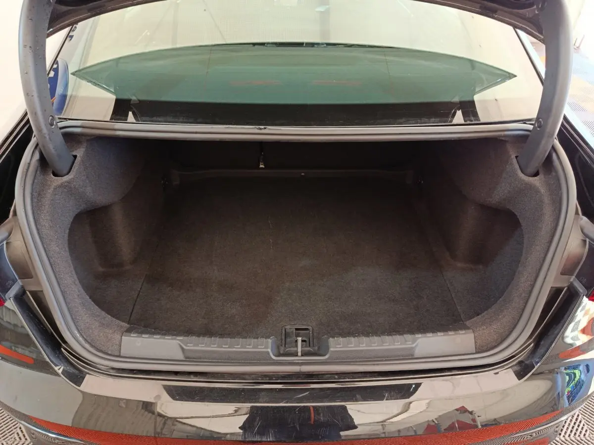 Coffre ouvert vu de l'arrière d'une Audi A3 noire 2022, espace de rangement vide et tapis gris foncé.