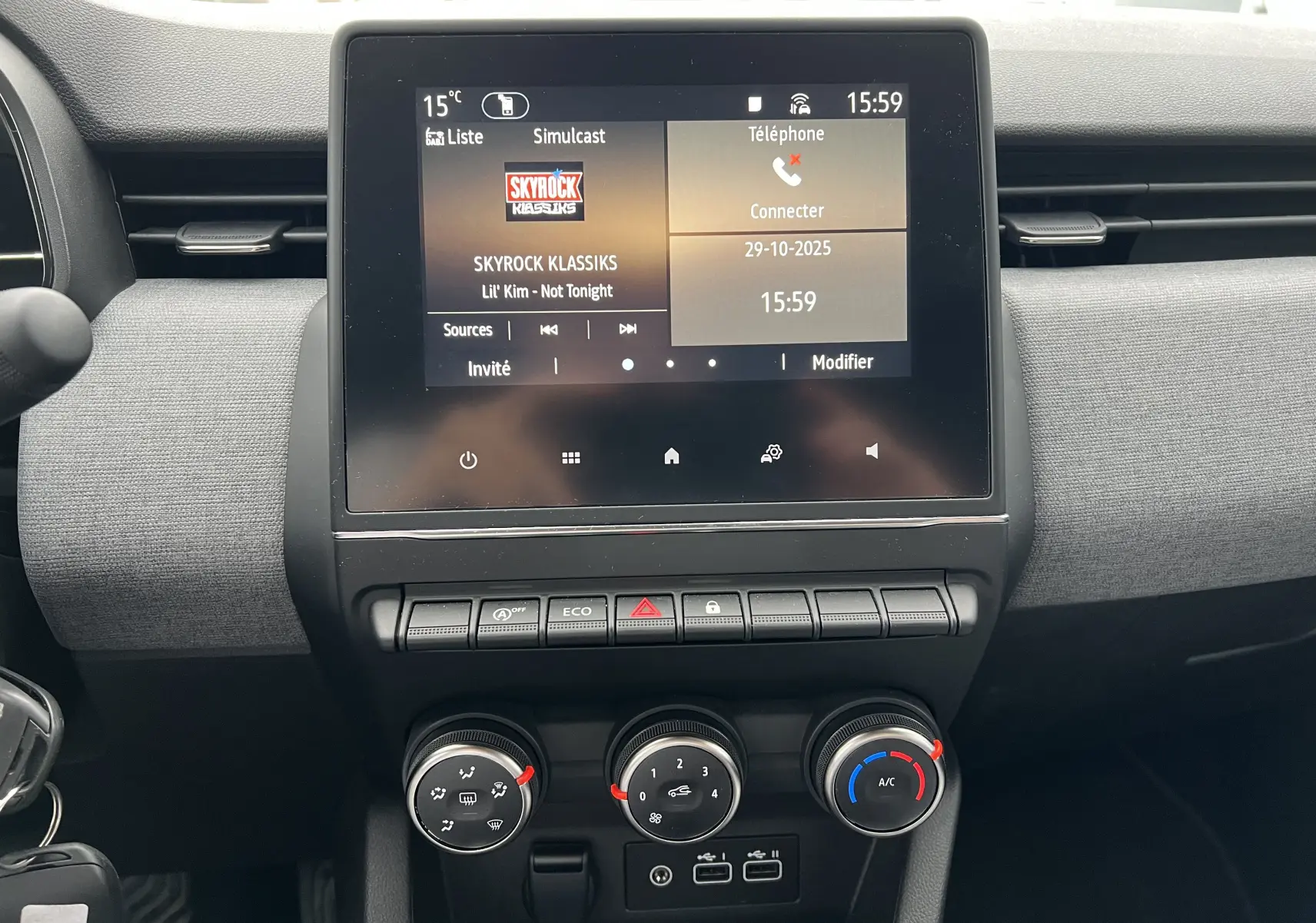 Tableau de bord de Renault Clio V blanc, vue frontale sur l'écran tactile multifonctions et commandes de climatisation.
